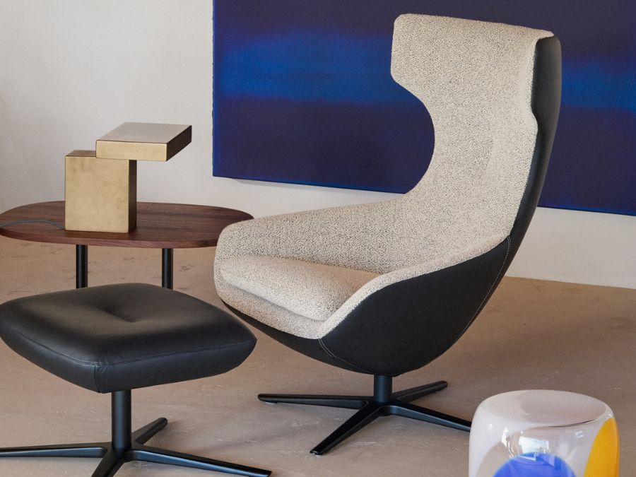 Leolux Caruzzo fauteuil met lichte stoffen binnenzijde en zwart lederen buitenschaal op draaivoet, met bijpassende hocker