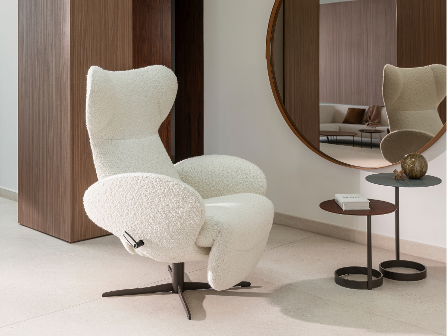 Jori Infinity relaxzetel in witte bouclé op een donkere draaivoet, naast twee ronde bijzettafels en een spiegel