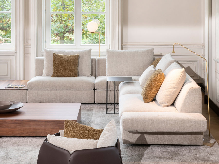 Lichtgrijze Jori Tigra Divanbase hoekzetel met longchair en okerkleurige kussens, notelaren salontafel en cognac lederen draaifauteuil met voetenbank in een klassiek salon