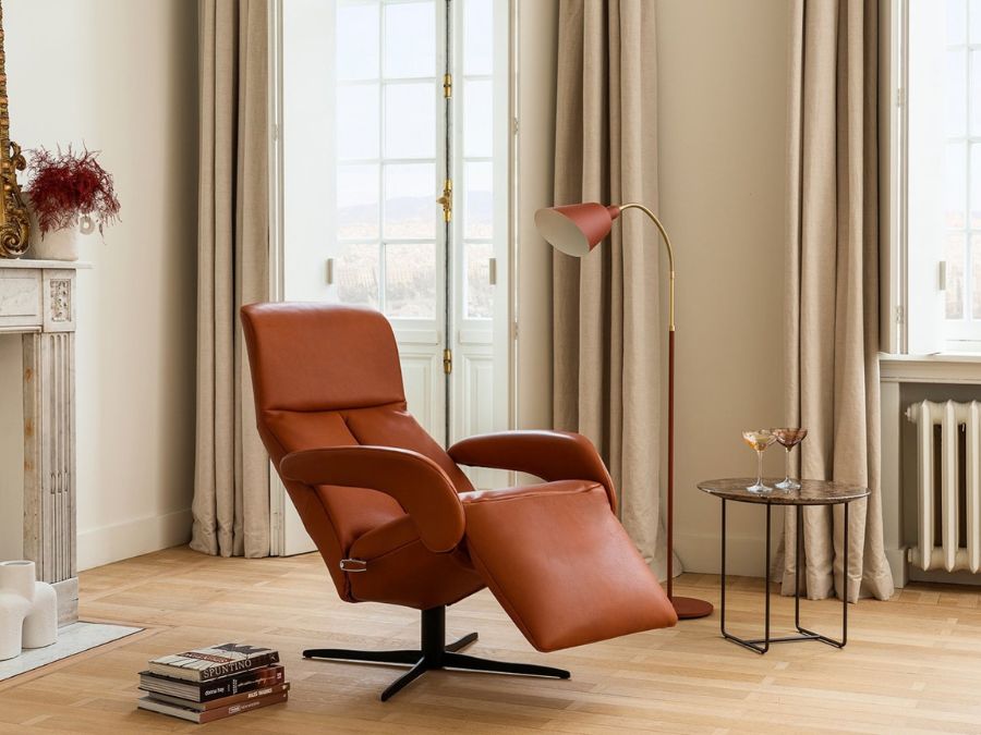 Jori relaxzetel in cognac leder in ligstand met uitgeklapte voetsteun, naast een bijzettafel en staanlamp in een klassiek interieur Jori relaxzetel in cognac leder in ligstand met uitgeklapte voetsteun, naast een bijzettafel en staanlamp in een klassiek interieur